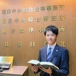 胸には弁護士バッジ。裁判などに日々向き合う＝大阪市北区（本人提供）