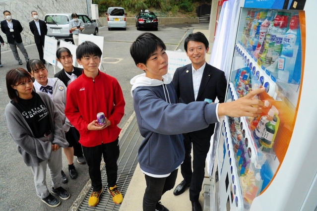 兵庫高校に設置された「おしゃべり自販機」で飲み物を買う生徒ら。斎藤知事の声でメッセージが流れる＝神戸市長田区寺池町１
