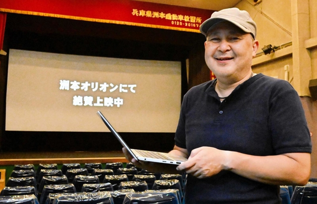 ノートパソコンを手に映写機を操作する洲本オリオンの野口仁支配人＝洲本市本町５