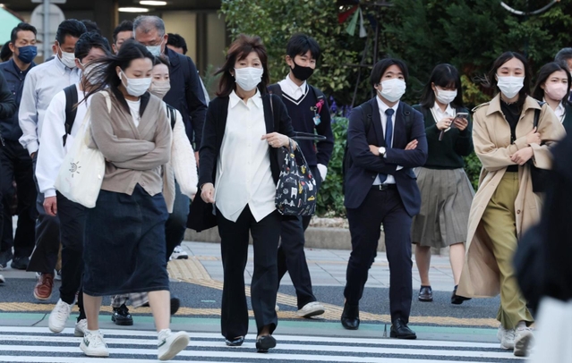 寒そうに肩をすくめながら横断歩道を渡る人たち＝１８日午後、神戸市中央区加納町４