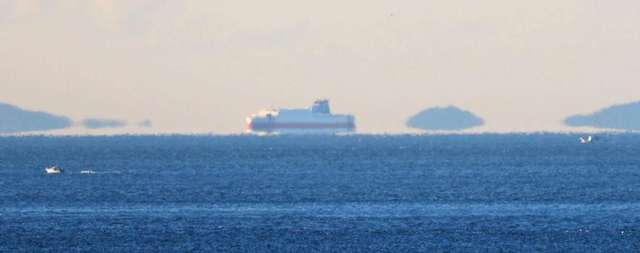 空気の揺らぎで海面から浮かんで見える島や船＝２６日午前、神戸市須磨区から（撮影・吉田敦史）