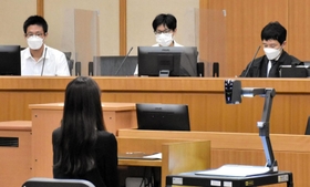 被告役の女性を前に、審理に臨む裁判官（右）と裁判員役の高校生＝神戸地裁