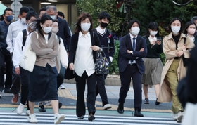 寒そうに肩をすくめながら横断歩道を渡る人たち＝１８日午後、神戸市中央区加納町４