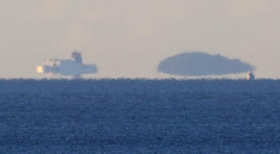 空気のゆらぎで浮かんで見える陸地と船＝２６日早朝、神戸市須磨区から（撮影・吉田敦史）