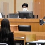 被告役の女性を前に、審理に臨む裁判官（右）と裁判員役の高校生＝神戸地裁