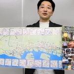 ２１年ぶりに紙製で発行された「震災モニュメントマップ」を掲げる藤本真一さん＝神戸市役所