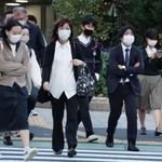 寒そうに肩をすくめながら横断歩道を渡る人たち＝１８日午後、神戸市中央区加納町４