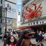 「河童のガジロウ」と手をつないで繁華街を歩くアルミカン赤阪侑子さん＝大阪市内