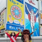 江崎グリコの電光看板前でポーズをとる福崎町ふるさと大使のアルミカン赤阪侑子さん（左）と河童のガジロウ＝大阪市内