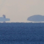 空気のゆらぎで浮かんで見える陸地と船＝２６日早朝、神戸市須磨区から（撮影・吉田敦史）