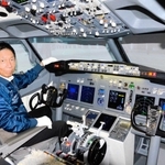 ボーイング７３７のフライトシミュレーターに座る伊藤世一社長。この操縦席で、朝ドラ「舞いあがれ！」第１話の冒頭シーンが撮影された＝神戸市長田区神楽町２、「テクノバード」
