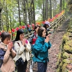 ３人の恩師の墓標の前で、手を合わせる卒業生ら＝群馬県上野村（提供写真）