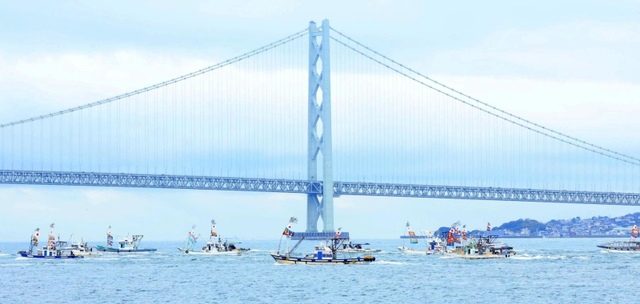 明石海峡大橋を背にパレードする漁船団＝１３日午後、明石市中崎１から（撮影・鈴木雅之）