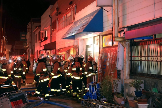 火災が起きた建物の状況を確認する消防隊員＝１５日午後９時３６分、長田区長楽町４
