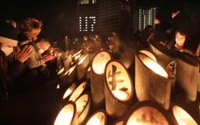 竹灯籠の前で手を合わせる人たち＝１７日午前５時４６分、神戸市中央区加納町６、東遊園地（撮影・吉田敦史）