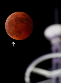 皆既食となった月に近づいていく左下の天王星。右は旧神戸港信号所＝８日午後８時２６分、神戸市中央区東川崎町１から（撮影・長嶺麻子）