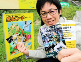 「近本ロード」の看板前でカードを持つ加東市職員＝加東市山口
