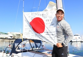 応援メッセージが書かれた日の丸をヨットに取り付け、笑顔を見せる木村啓嗣さん＝１２日午後、西宮市西宮浜４、新西宮ヨットハーバー（撮影・斎藤雅志）