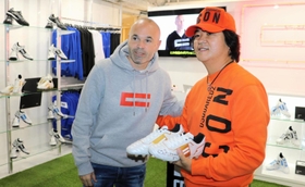 自ら立ち上げたサッカーシューズブランドの正式オープンに合わせ、ファンと記念撮影に応じるイニエスタ選手（左）＝神戸市中央区