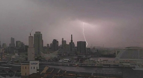 灰色の雲の中から市街地へ落ちる雷＝23日午後、神戸市中央区東川崎町１から（撮影・長嶺麻子）