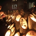 竹灯籠の前で手を合わせる人たち＝１７日午前５時４６分、神戸市中央区加納町６、東遊園地（撮影・吉田敦史）