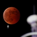 皆既食となった月に近づいていく左下の天王星。右は旧神戸港信号所＝８日午後８時２６分、神戸市中央区東川崎町１から（撮影・長嶺麻子）