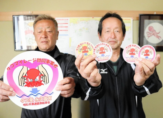タコマイレージ制度で、マダコの提供者に配ったステッカーを持つ明石市漁業協同組合連合会遊漁船部会の松本正勝会長（右）ら＝明石市二見町東二見
