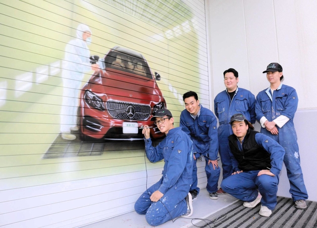 自動車の塗装に用いるエアブラシを使って巨大アートを完成させた金属塗装コースの学生ら＝姫路市市之郷
