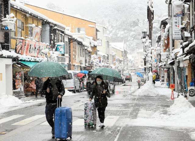 足元に気をつけながら雪の温泉街を歩く観光客ら＝１９日午前、豊岡市城崎町湯島（撮影・岡本好太郎）