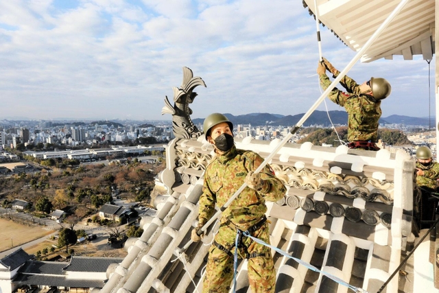 姫路城大天守の屋根に乗って清掃するレンジャー隊員＝姫路市本町