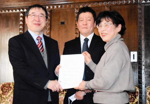 神戸大経済経営研究所の家森信善所長（左）に、広岡家文書の寄託契約書を手渡す西野久子さん。中央は神大の高槻泰郎准教授＝神戸市灘区六甲台町、神戸大兼松記念館