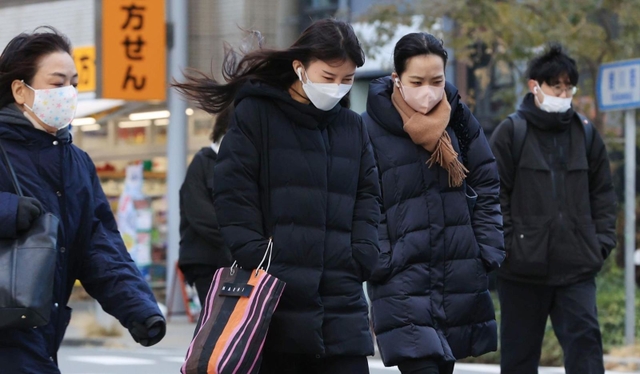 冷たい風に身を縮める人たち＝２３日午前、神戸市中央区