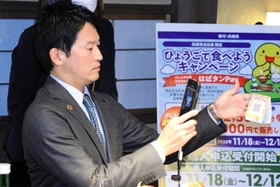 スマートフォンを手に「はばタンＰａｙ（ペイ）」の使い方を説明する斎藤元彦知事＝神戸市東灘区御影塚町１、神戸酒心館