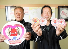 タコマイレージ制度で、マダコの提供者に配ったステッカーを持つ明石市漁業協同組合連合会遊漁船部会の松本正勝会長（右）ら＝明石市二見町東二見