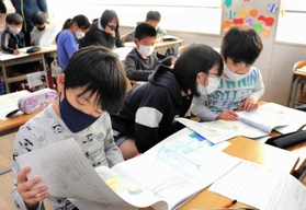 「アッコちゃん」の生い立ちや、家族の思いが詰まった絵本を読む５年生の児童たち＝神戸市灘区、西灘小学校