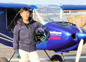 新明和工業の宮内空野さん。自身も携わったヤマハ発動機との共同開発機の前で＝静岡県静岡市清水区、富士川滑空場