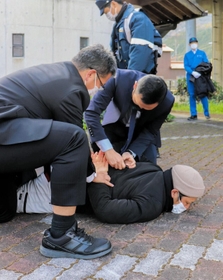 不審者役を取り押さえる警察官＝１６日午後、智頭急行苔縄駅