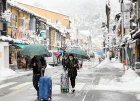 足元に気をつけながら雪の温泉街を歩く観光客ら＝１９日午前、豊岡市城崎町湯島（撮影・岡本好太郎）