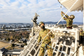 姫路城大天守の屋根に乗って清掃するレンジャー隊員＝姫路市本町