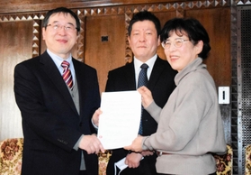 神戸大経済経営研究所の家森信善所長（左）に、広岡家文書の寄託契約書を手渡す西野久子さん。中央は神大の高槻泰郎准教授＝神戸市灘区六甲台町、神戸大兼松記念館