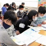 「アッコちゃん」の生い立ちや、家族の思いが詰まった絵本を読む５年生の児童たち＝神戸市灘区、西灘小学校