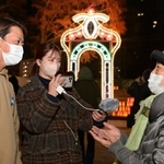 来場者に阪神・淡路大震災の経験を聞く「１・１７希望の架け橋」の藤原祐弥さん（左）ら＝１０日夜、神戸市中央区加納町６（撮影・秋山亮太）