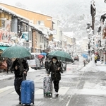 足元に気をつけながら雪の温泉街を歩く観光客ら＝１９日午前、豊岡市城崎町湯島（撮影・岡本好太郎）