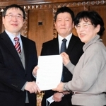 神戸大経済経営研究所の家森信善所長（左）に、広岡家文書の寄託契約書を手渡す西野久子さん。中央は神大の高槻泰郎准教授＝神戸市灘区六甲台町、神戸大兼松記念館