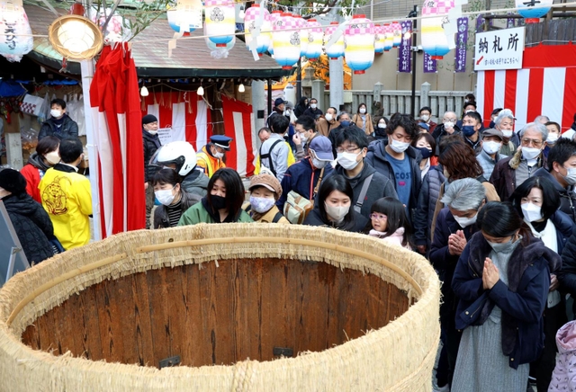 酒樽にさい銭を投げ入れ、手を合わせる参拝客ら＝９日、神戸市兵庫区西柳原町、蛭子神社（撮影・長嶺麻子）