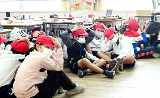 神戸市内の小学校で行われた避難訓練。余震も想定し、子どもたちは頭を手で押さえた＝２０２２年１１月（撮影・中西幸大）