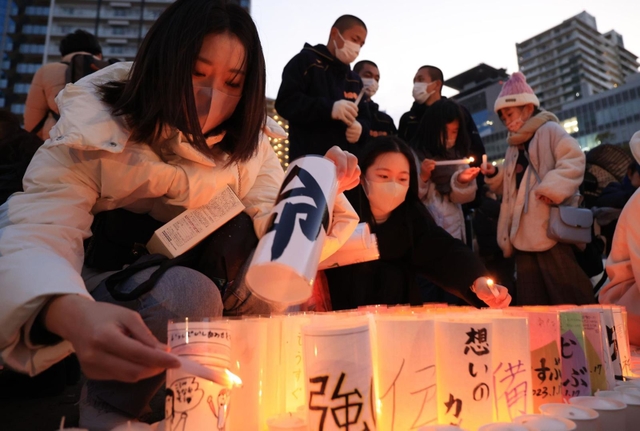 紙灯籠に火をともすボランティアら＝１６日午後、神戸市中央区加納町６、東遊園地