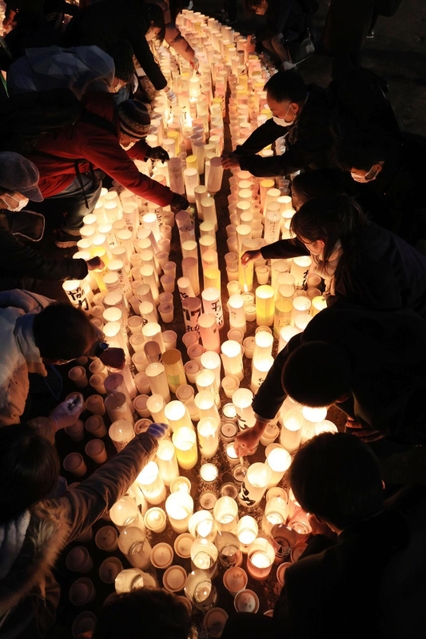 紙灯籠に火をともすボランティアら＝１６日午後、神戸市中央区加納町６、東遊園地