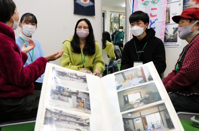 阪神・淡路大震災の話を含め、和やかに語り合う高校生、大学生と住民ら。手前は震災直後の写真＝神戸市灘区中郷町５、地域共生拠点・あすパーク