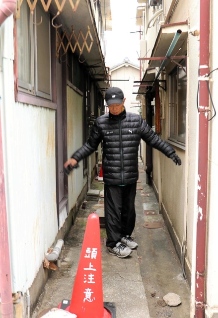 危険密集市街地で、家と家の間の狭い通路を示す駒ケ林まちづくり協議会会長の浦井清五さん＝神戸市長田区駒ケ林町１
